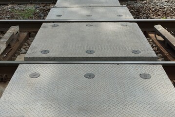 pedestrian crossing over the railway from gray concrete slabs among steel rails