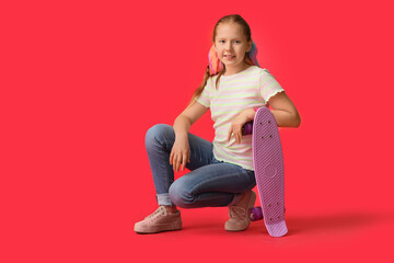 Obraz na płótnie Canvas Cute redhead girl with skateboard on color background
