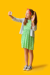 Cute redhead girl taking selfie on color background