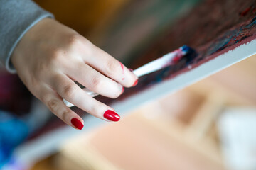 Female artist's hand holding brush and painting