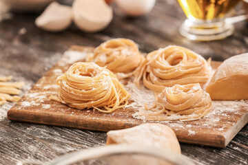 Board with raw pasta and flour on table