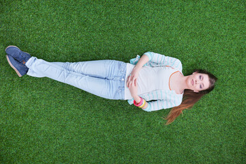 Beautiful young woman lying on the green grass