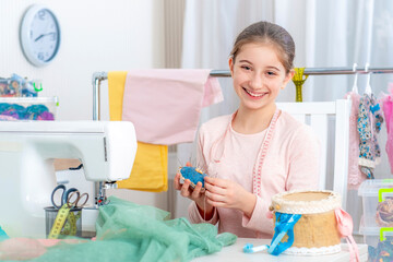 Little tailor girl is working with sewing machine and smiling