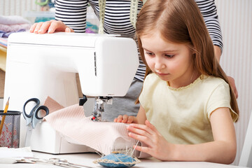 little girl carefully working with modern sewing machine
