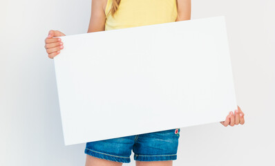 Teen girl holding blank white sheet of paper with free copy space