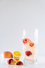 A refreshing summer drink made from soda and fruit. strawberries, lemon, apple. fruit in a glass, flying spray. healthy eating. quenching thirst