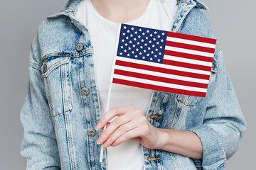 Female hand holds America flag isolated over grey background, celebration 4th of july independence...