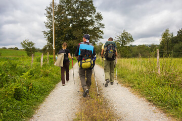 Spain - 10/01/2019: Three unknown pilgrims walking on Camino de Santiago. Group of tourists with...