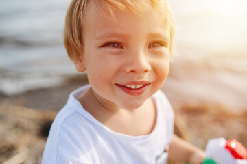 Portrait of a handsome little blond boy by the water under gentle sun