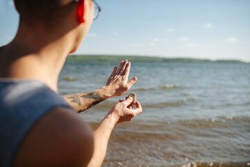 Adult man aiming with his hand, throwing pebbels against lake water on sunny day