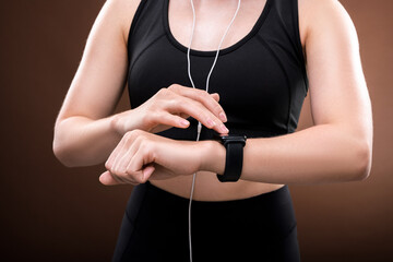 Middle section of young sportswoman in black tracksuit touching wristwatch