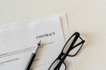 close up macro view of a contract document with eye glasses and a pen
