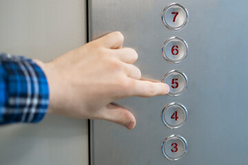 a close up hand pushing a button  in the lift elevator cabin