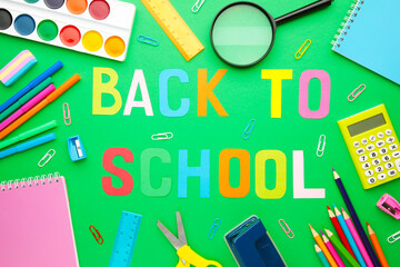 School supplies with inscription back to school on green background
