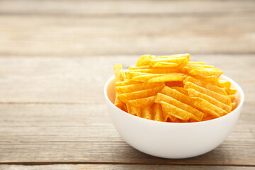 Potato chips on bowl on grey wooden background