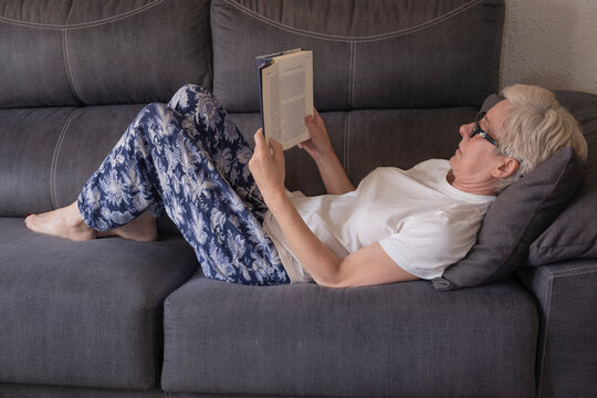 Mujer con gafas leyendo en el sof&aacute; tumbada