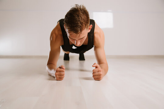 Young Man In Sport Stylish Clothes Standing In Plank Pose Or Doing Horizontal Push-up In Living Room At Home.