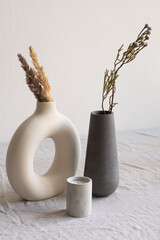 Two ceramic handmade vases with dried wildflowers and spikes and aromatic candle - obrazy, fototapety, plakaty