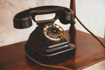 An old telephone with a wire is on the shelf. Soviet antique telephone of the 1940s