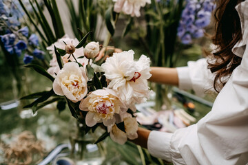 Florist showing how to make a bouquet of pink pale peonies at a workshop.