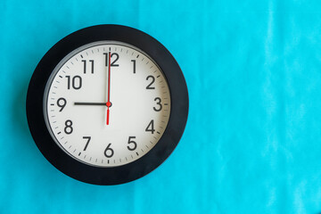 A black and white clock on a blue wall