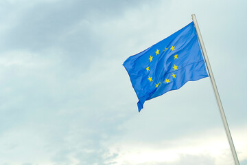 European Union flag on a cloudy sky background. EU flag in a wind.