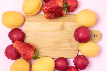 Tasty Fruits Apricots Plums Strawberry Fruits and Berry Summer Background Pink Background Frame Copy Space Wooden Cut Board