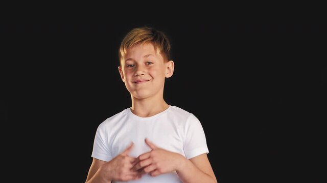 Like gesture. Approval sign. Confident boy showing thumbs up smiling isolated on black background.