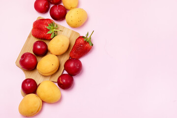 Tasty Fruits Apricots Plums Strawberry Fruits and Berry on Wooden Cutting Board Summer Pink Background Top View Copy Space
