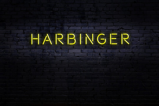 Neon sign. Word harbinger against brick wall. Night view