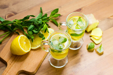 Two glasses with a homemade drink of lemon, mint and ginger