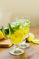 Two glasses with a homemade drink of lemon, mint and ginger