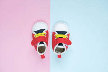 Tiny baby footwear on coloured background. Infant's shoes for boys and girls, cute sneakers.