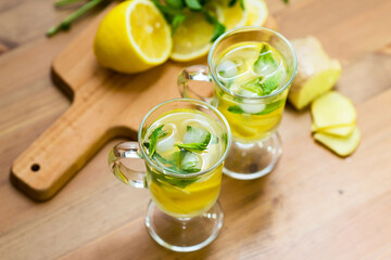 Two glasses with a homemade drink of lemon, mint and ginger