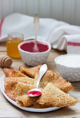 Rye and whole grain pancakes served with sour cream, honey and strawberry sauce. Rustic style.