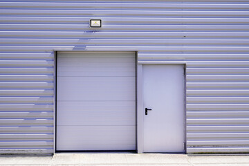 Fototapeta premium entrance roll-down shutters on gray building fire exit door in commercial industrial unit