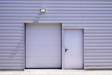 entrance roll-down shutters on gray building fire exit door in commercial industrial unit