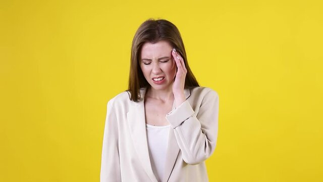 Headache. Tired sad upset young businesswoman on yellow background. Concept Headaches, Migraines, Diseases, Overwork Of People. Looking at camera put hands on head with headache