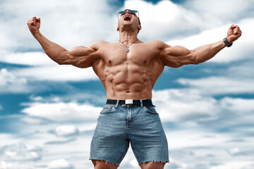 Muscular man showing muscles on sky background. Strong male naked torso abs