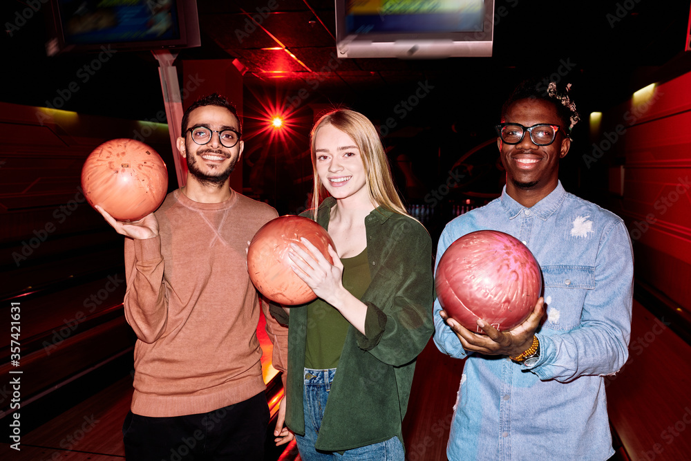 Poster Two young intercultural men and blond Caucasian girl with bowling balls