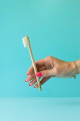 eco organic white bamboo toothbrush in hand on blue background. Copy space, dental care concept.