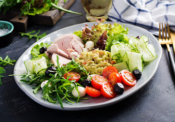 Ketogenic diet. Dinner dish with boiled pork meat, avocado guacamole, tomatoes, cucumbers, mozzarella cheese, black olives  and arugula. Detox and healthy concept. Keto food.