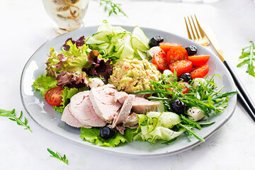 Ketogenic diet. Dinner dish with boiled pork meat, avocado guacamole, tomatoes, cucumbers, mozzarella cheese, black olives  and arugula. Detox and healthy concept. Keto food.