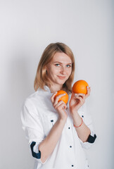 Female doctor holds two citrus fruits in hands.