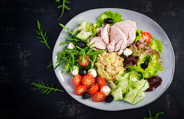 Ketogenic diet. Dinner dish with boiled pork meat, avocado guacamole, tomatoes, cucumbers, mozzarella cheese, black olives  and arugula. Detox and healthy concept. Keto food. Overhead, top view