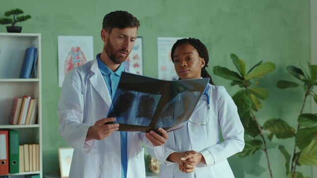 Chief doctor and nurse assistant examine a fluorography lungs x-ray scan image for medical analysis. Multi-ethnic medical staff. Hospitals. Healthcare. Cooperation.
