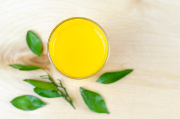 Tangerine juice in a transparent glass with leaves.