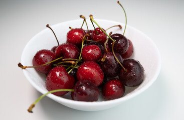 Obraz na płótnie Canvas Tasty cherries in a white bowl on white table