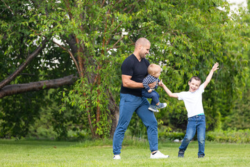 Father  plays with little boy son, hug baby  in the park on a warm summer day. Happy childhood concept.  Happiness and harmony of family life. Great family vacation.