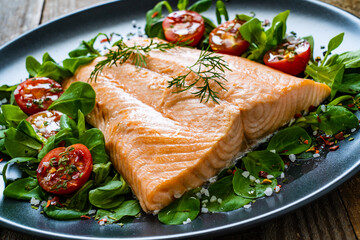 Steamed salmon fillet with vegetables on wooden table